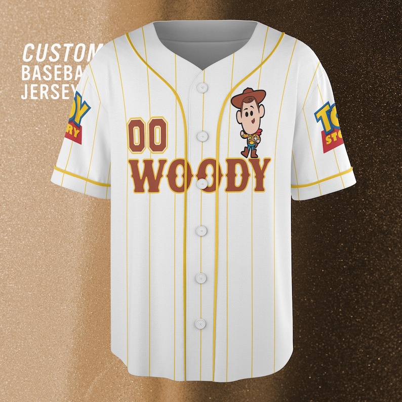 Może przedstawiać: Biała koszulka baseballowa z ż&oacute;łtymi cienkimi paskami, z postacią Woody'ego z Toy Story. Koszulka ma numer "00" i imię "WOODY" w brązowych literach. Tekst "CUSTOM BASEBALL JERSEY" jest widoczny po lewej stronie.