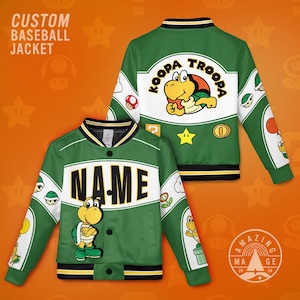 Può includere: Giacca da baseball verde con design Koopa Troopa. La giacca presenta una striscia bianca sul petto e sulla schiena con le scritte "KOOPA TROOPA" e "NAME". La giacca ha un bordo nero e giallo ed è decorata con varie grafiche di Super Mario Bros.