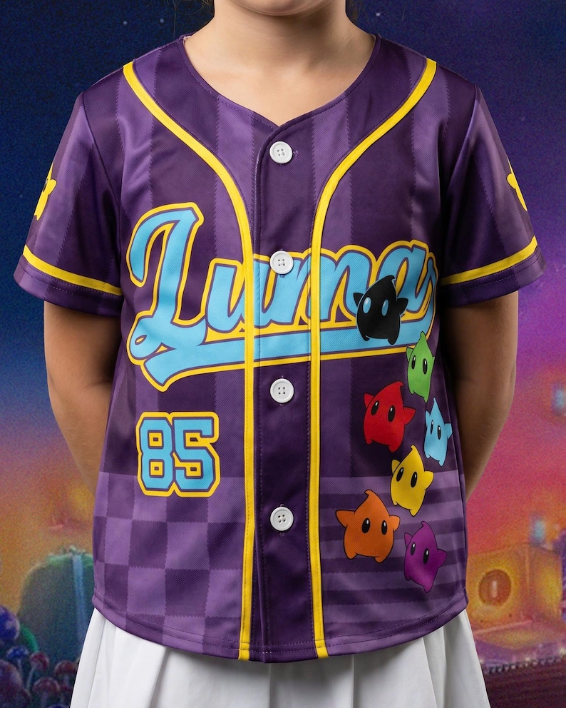 Może przedstawiać: Fioletowa koszulka baseballowa zapinana na guziki z napisem "Luna" jasnoniebieską kursywą, liczbą "85" w kolorze jasnoniebieskim oraz pionowym układem kolorowych postaci w kształcie gwiazd w kolorach czarnym, zielonym, czerwonym, niebieskim, ż&oacute;łtym, pomarańczowym i fioletowym.