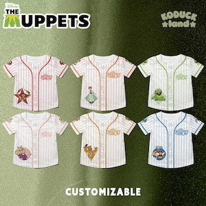 May include: Six customizable baseball jerseys featuring Muppets characters. Each jersey has a different color scheme and Muppet character patch. The jerseys have the text "The Muppet Show" on the chest and the word "Customizable" at the bottom.