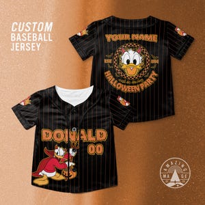 Op de afbeelding: Zwart honkbalshirt met oranje krijtstrepen en een witte kraag. De voorkant toont "DONALD" en het nummer "00". De achterkant heeft "YOUR NAME" boven een Donald Duck Halloween-ontwerp. De tekst "CUSTOM BASEBALL JERSEY" is ook zichtbaar.