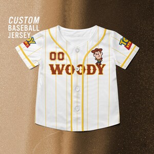 Może przedstawiać: Biała koszulka baseballowa z ż&oacute;łtymi cienkimi paskami, z napisem "WOODY" i numerem "00" w brązowych literach. Postać z kresk&oacute;wki znajduje się po prawej stronie. Tekst "CUSTOM BASEBALL JERSEY" znajduje się w lewym g&oacute;rnym rogu.