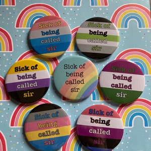May include: Six round buttons with different pride flag designs. Each button has the text "Sick of being called sir" printed on it.