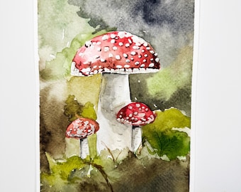 Könnte beinhalten: Aquarellmalerei von drei roten und weißen Pilzen mit weißen Punkten auf einem grünen und braunen Hintergrund.