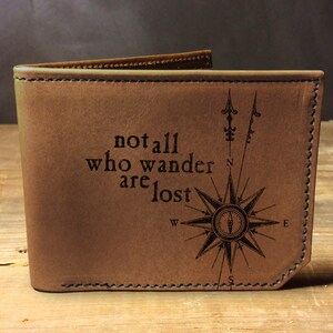 May include: Brown leather wallet with a compass design and the quote "not all who wander are lost".