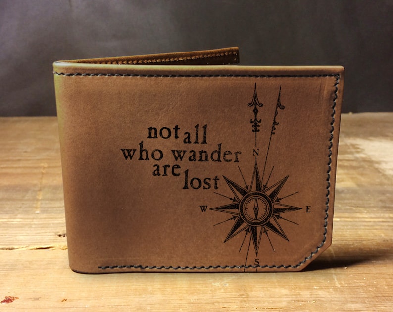 May include: Brown leather wallet with a compass design and the quote "not all who wander are lost".