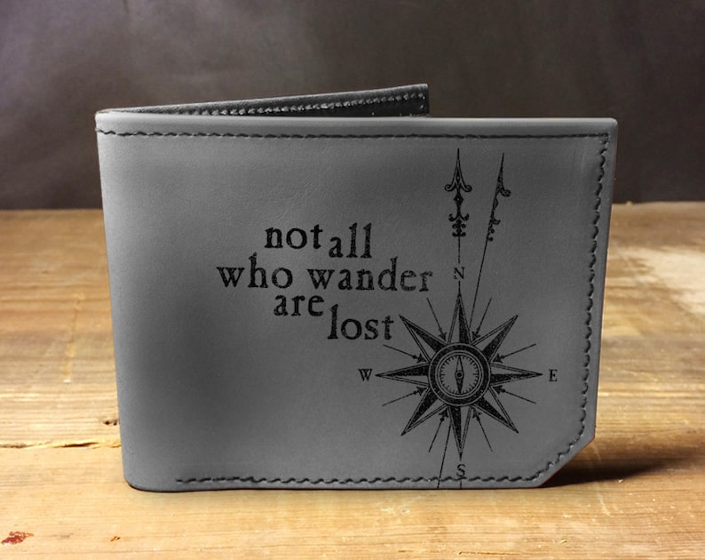May include: Gray leather wallet with a compass design and the quote "not all who wander are lost".