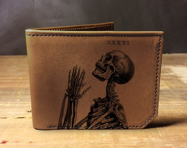 May include: Brown leather wallet with a skeleton design and the Roman numeral 'XXXVI' engraved on the front.