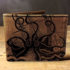 May include: A brown leather wallet with a black and white illustration of an octopus attacking a ship. The illustration is detailed and includes waves and the ship's mast.