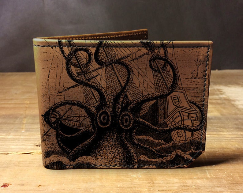May include: A brown leather wallet with a black and white illustration of an octopus attacking a ship. The illustration is detailed and includes waves and the ship's mast.