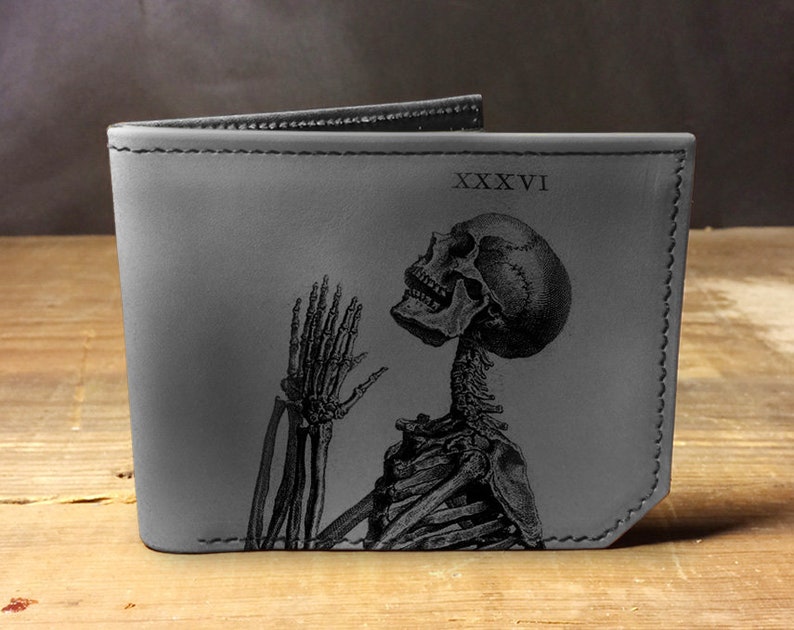 May include: A gray leather wallet with a black skeleton design and the Roman numeral 'XXXVI' printed on the front.