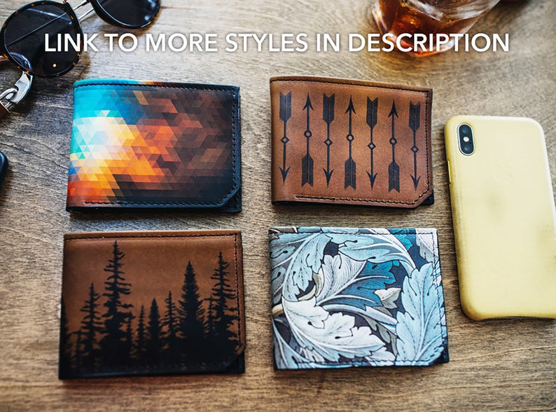 May include: Four leather wallets with unique designs are displayed on a wooden surface. One wallet features a geometric pattern in shades of orange, blue, and black. Another has an arrow design, and a third depicts a forest silhouette. The fourth wallet has a floral pattern.