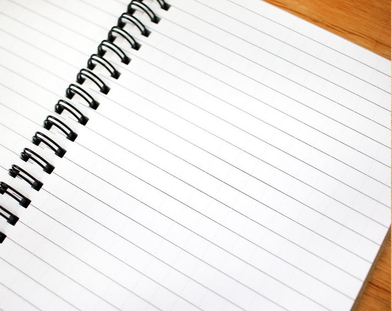 May include: A white spiral bound notebook with lined pages. The notebook is open and the binding is on the left side of the image.