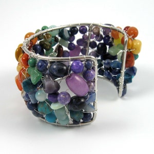May include: A silver wire wrapped bracelet with a rainbow of semi-precious stones. The bracelet is made with a variety of stones, including amethyst, turquoise, and carnelian.