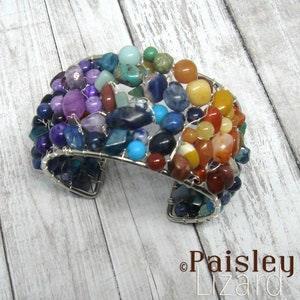 May include: A rainbow-colored wire-wrapped bracelet with a variety of gemstones, including amethyst, turquoise, and carnelian. The bracelet is made with silver wire and has a unique, handcrafted look.
