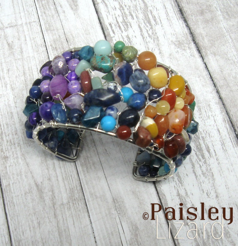 May include: A rainbow-colored wire-wrapped bracelet with a variety of gemstones, including amethyst, turquoise, and carnelian. The bracelet is made with silver wire and has a unique, handcrafted look.