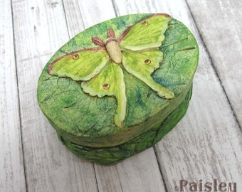 May include: A green and brown oval-shaped box with a sculpted green luna moth on the lid. The box is made of paper mache and has a textured surface.