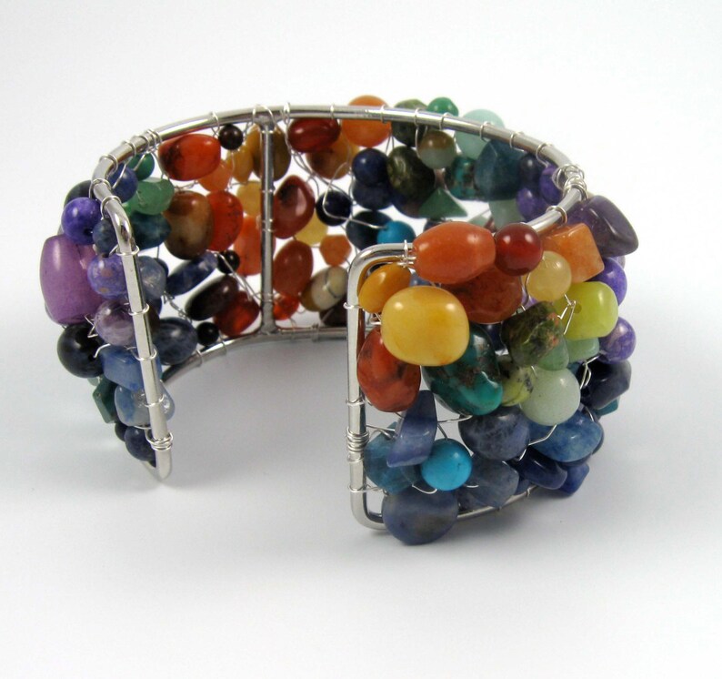 May include: A silver wire wrapped bracelet with a rainbow of colorful gemstones. The bracelet is made with a variety of stones, including amethyst, carnelian, citrine, turquoise, and lapis lazuli.