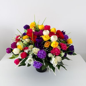 May include: A colourful floral arrangement with red, yellow, purple, and white tulips and other flowers. The flowers are arranged in a black pot, creating a cheerful display. Ideal for home decor, this arrangement adds a touch of vibrancy to any space.