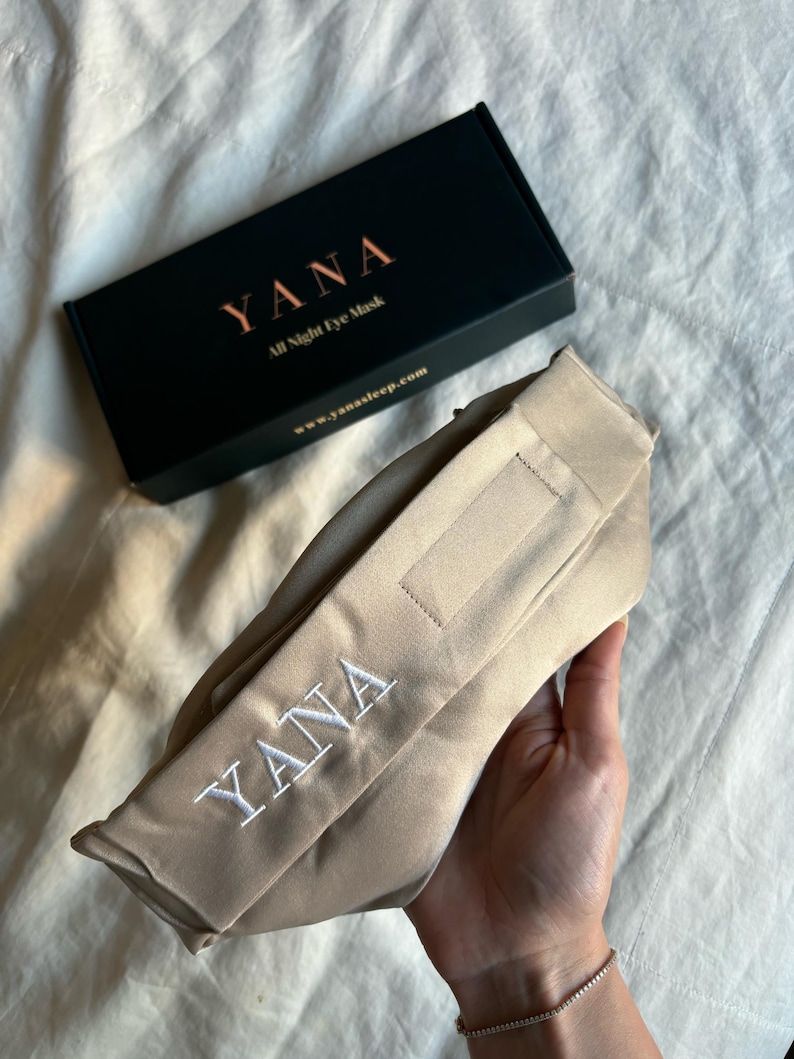 May include: A beige eye mask with the embroidered word "YANA" in white, next to a black box with the word "YANA" and the text "All Night Eye Mask". The website www.yanasleep.com is also visible.