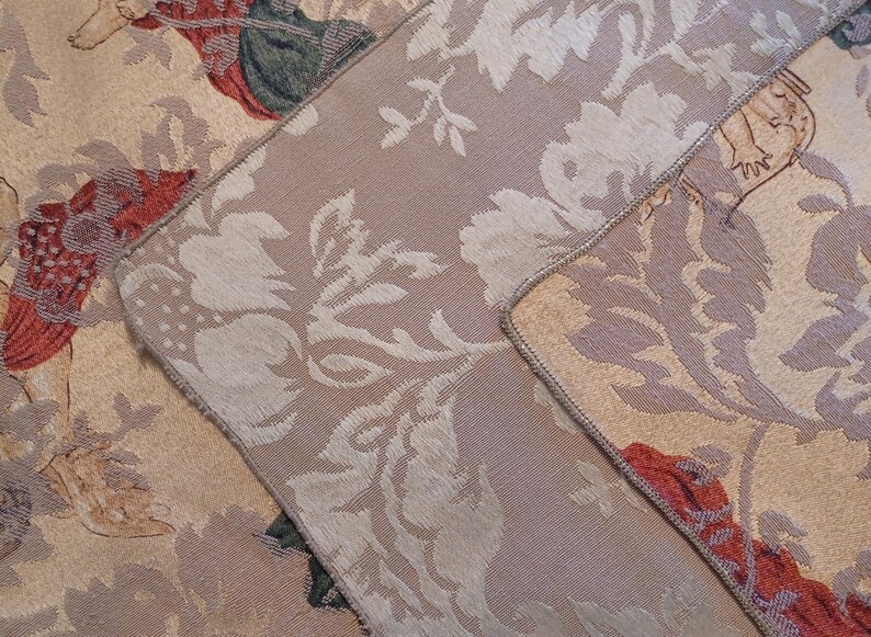 K&ouml;nnte beinhalten: Nahaufnahme eines Abschnitts eines floralen Wandteppichs. Der Stoff weist ein sich wiederholendes Muster aus gro&szlig;en, stilisierten Blumen in Creme und Beige mit Akzenten in Rot, Gr&uuml;n und Braun auf. Die Kanten sind mit einem kontrastierenden Rand versehen.