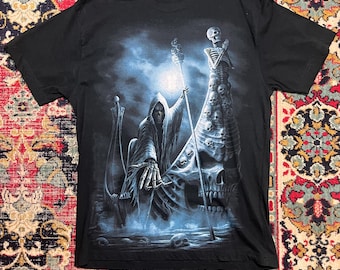 May include: Black t-shirt with a detailed graphic of the Grim Reaper in a hooded cloak, holding a staff, with a skull and skeleton design. The artwork has blue and white accents, creating a dramatic, fantasy theme.