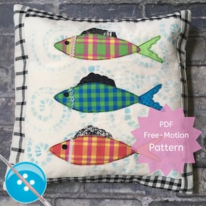 May include: A white pillow with a black and white checkered border. The pillow features three colorful fish appliques with plaid fabric and black and white accents. The pillow is labeled "PDF Free-Motion Pattern".