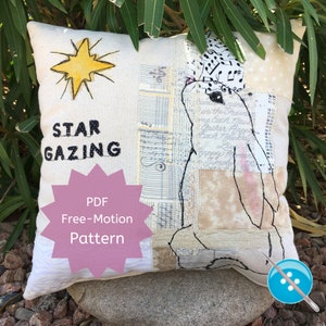 May include: A white pillow with a stargazing theme. The pillow features a hand-drawn star, the words "STAR GAZING", and a free-motion embroidery design of a rabbit. The pillow is made from a patchwork of fabrics, including music sheets and other printed papers. The text "PDF Free-Motion Pattern" is printed on a pink starburst.