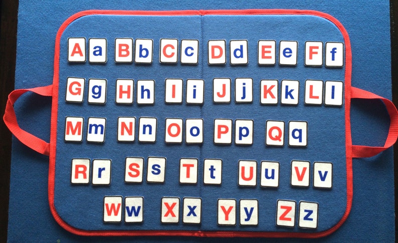 Puede incluir: Una alfombra de fieltro azul con ribetes y asas rojas. La alfombra tiene cuadrados blancos con letras rojas y azules. Las letras est&aacute;n dispuestas en orden alfab&eacute;tico. Las letras son Aa Bb Cc Dd Ee Ff Gg Hh Ii Jj Kk Ll Mm Nn Oo Pp Qq Rr Ss Tt Uu Vv Ww Xx Yy Zz.