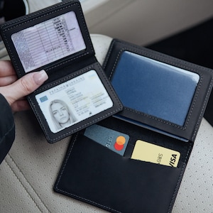 May include: Black leather wallet with multiple compartments, including slots for cards and clear windows for identification documents. The wallet is open, displaying a driver's license and credit cards.