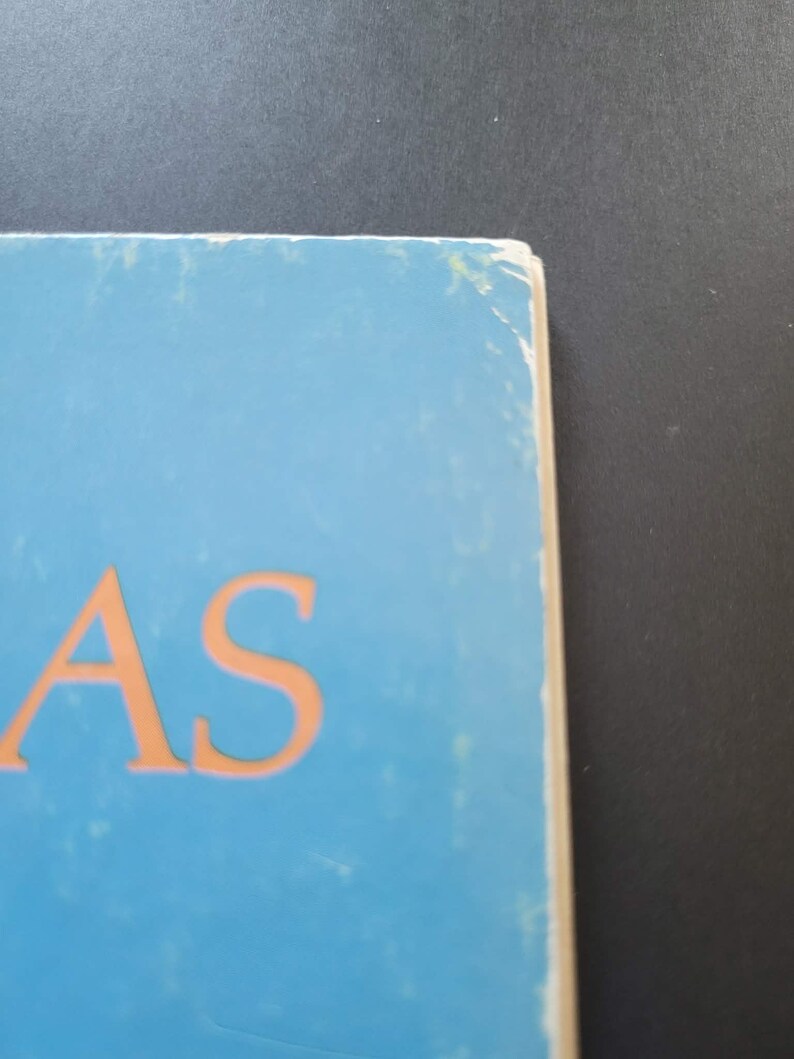 K&ouml;nnte beinhalten: Nahaufnahme eines Buchcovers mit den orangefarbenen Buchstaben "AS" auf hellblauem Hintergrund. Die Kanten des Buches sind sichtbar und weisen Abnutzungserscheinungen auf. Der Hintergrund ist dunkelgrau.