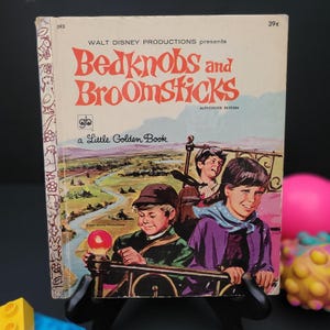 May include: A vintage Little Golden Book with a yellow cover featuring the title "Bedknobs and Broomsticks" in red and black lettering. The book is a Walt Disney Productions authorized edition and features a picture of three children on a bed.