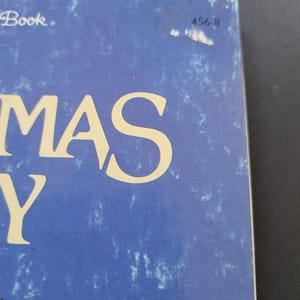 K&ouml;nnte beinhalten: Nahaufnahme eines Buchcovers mit dem Wort "MAS" in gro&szlig;en, gelben Buchstaben. Das Cover ist ein verwaschenes Blau mit wei&szlig;en Sprenkeln. In der oberen rechten Ecke stehen die Zahlen "456-8".