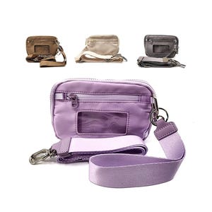 May include: A rectangular lavender crossbody bag featuring a front zippered pocket, a clear plastic ID window, and a matching detachable fabric strap with silver-toned metal hardware. Three additional bags in tan, beige, and gray are shown above.