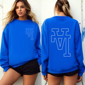 May include: A royal blue sweatshirt with a white outline of the letters "LA" on the front and back. The sweatshirt has long sleeves and a crew neck.