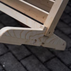 May include: Close-up of a wooden swing set base, showing the natural wood grain and a small hole in the wood.