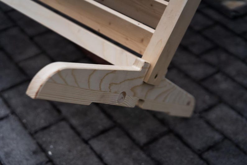 May include: Close-up of a wooden swing set base, showing the natural wood grain and a small hole in the wood.