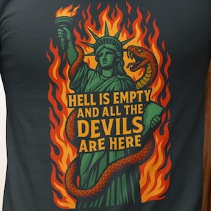 Puede incluir: Camiseta de color verde oscuro con un diseño gráfico de la Estatua de la Libertad en llamas, una serpiente y el texto "HELL IS EMPTY AND ALL THE DEVILS ARE HERE". El diseño utiliza verde, naranja y amarillo.