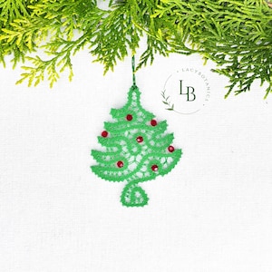 Può includere: Un ornamento ad albero di Natale in pizzo verde con accenti di perline rosse, appeso a un filo verde. L'ornamento è posto su uno sfondo bianco, con fogliame verde negli angoli superiori. L'ornamento ha il testo "Lacy Botanics" in un cerchio.