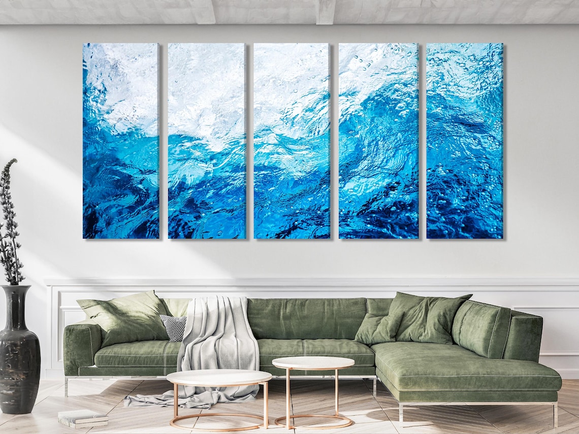 Ocean waves artwork on a white wall above a blue armchair and sofa