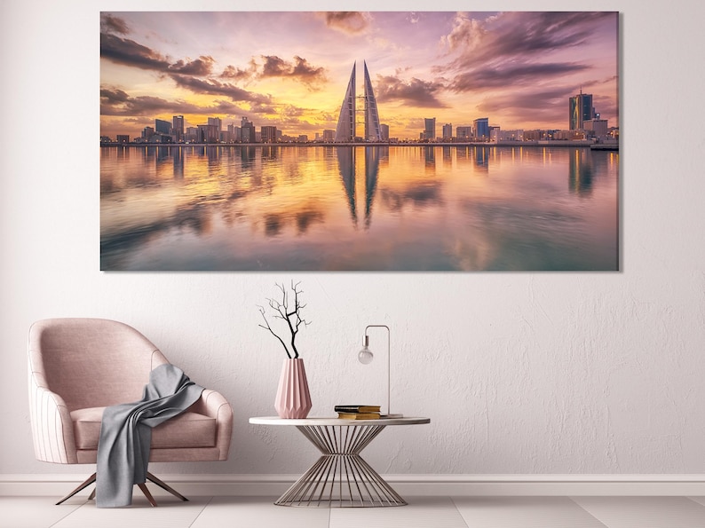 Sunset city skyline with a tall pointed tower and reflections on calm water