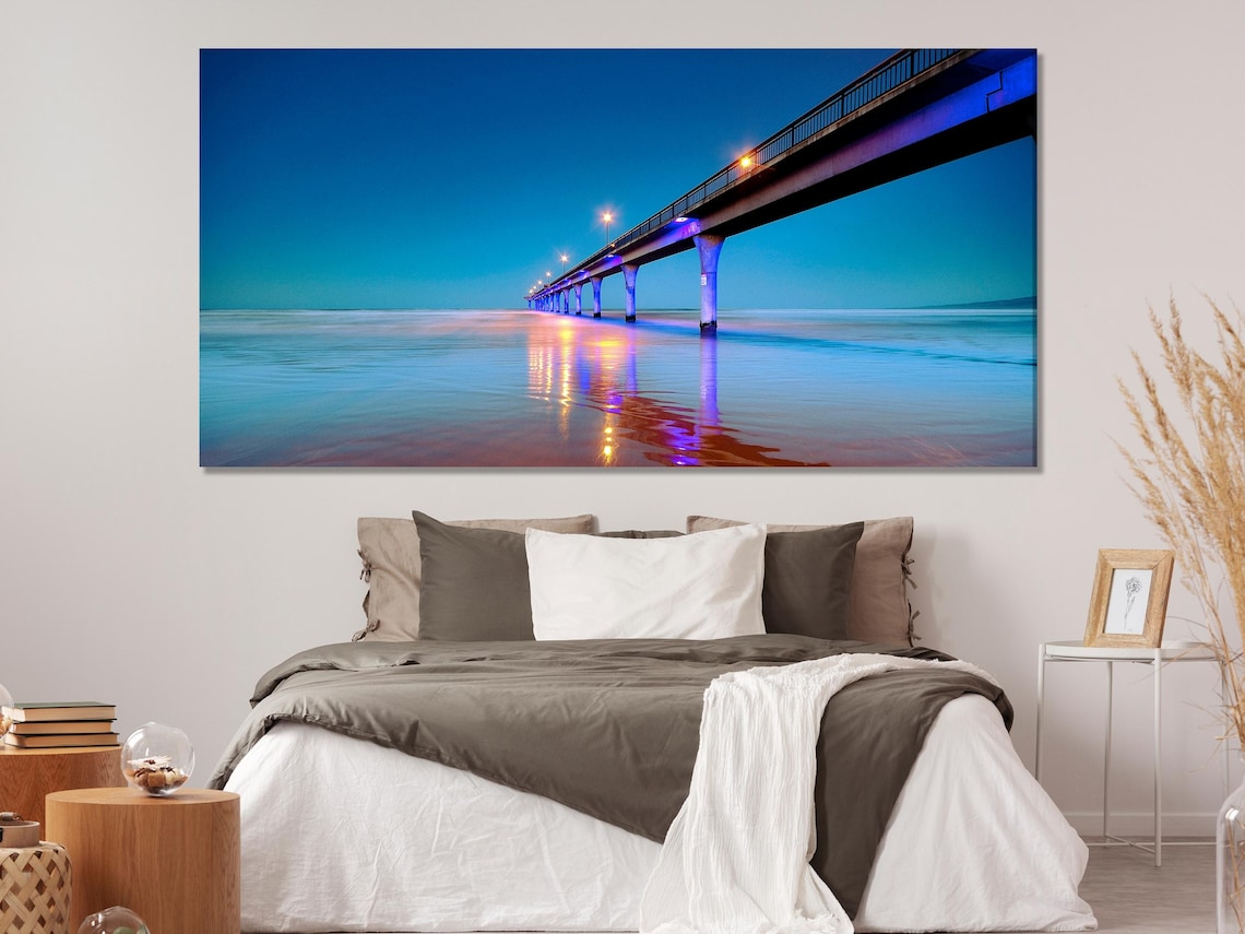 Three-panel night seascape showing an illuminated pier and glowing reflections on calm ocean water detail view