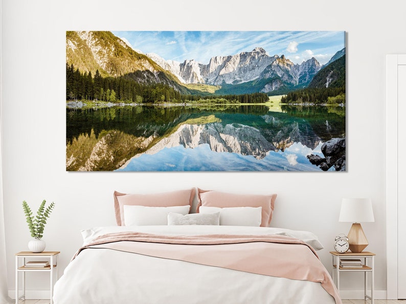 A panoramic mountain-and-lake landscape with conifer forests and clear water reflections, framed by bright sky blues and pale rocky peaks