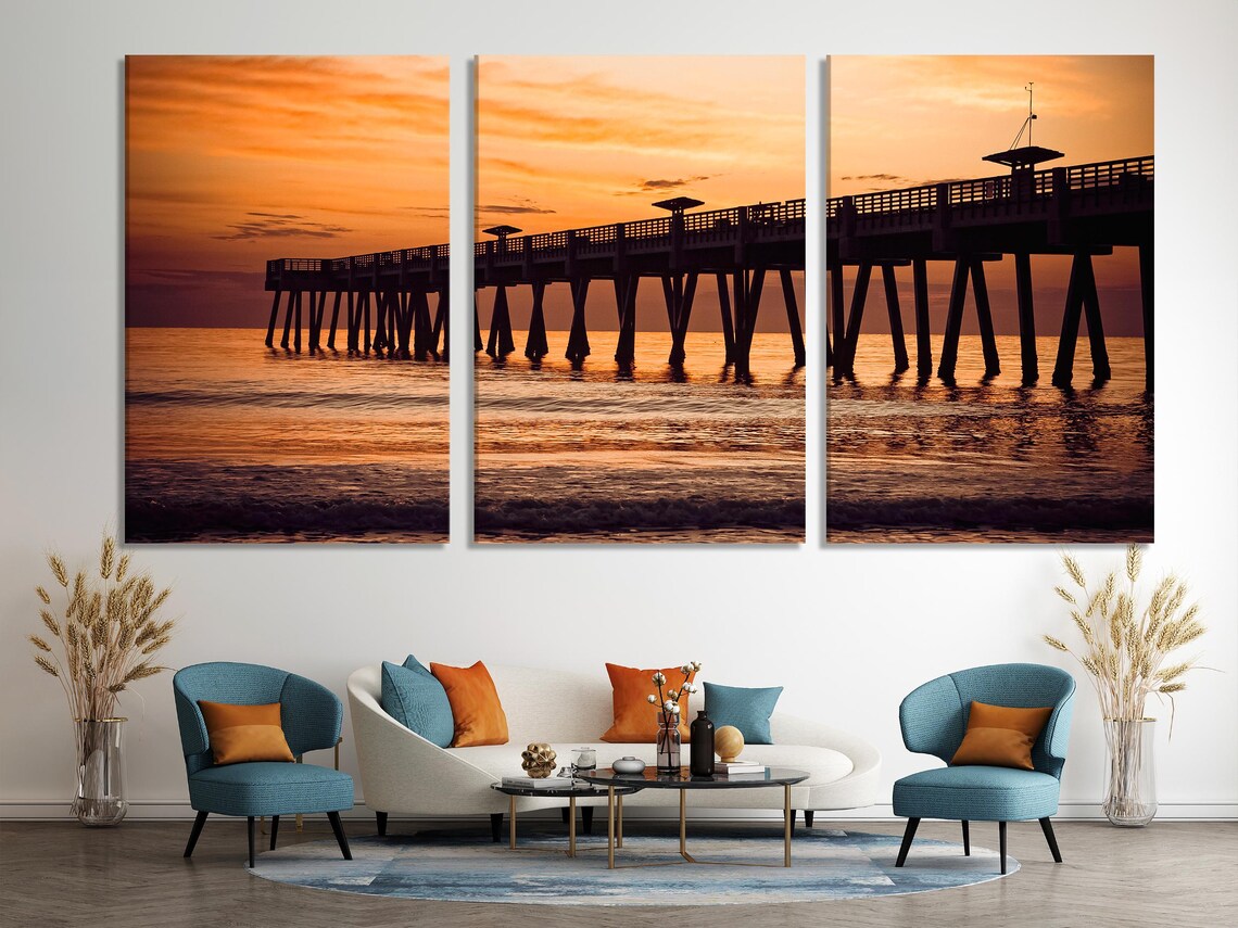 Artwork of a sunset ocean pier scene displayed in a living room