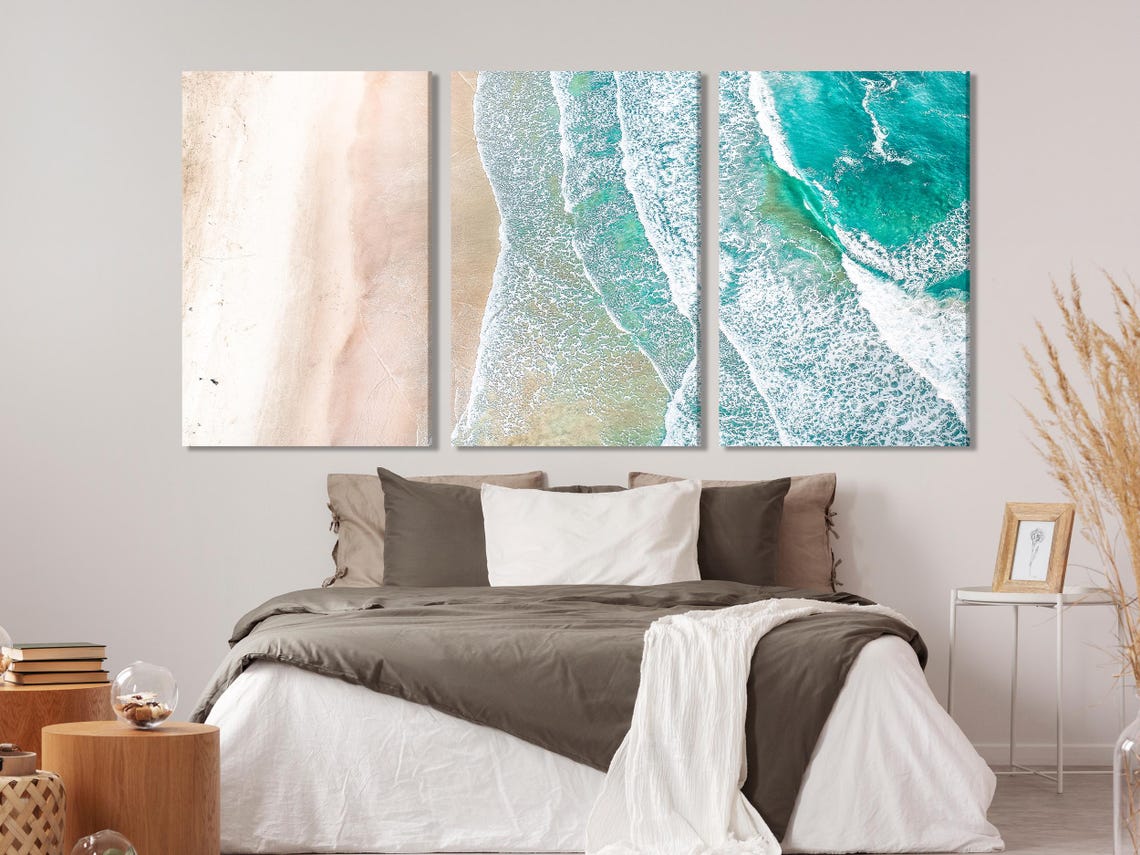 Bedroom scene with a large ocean shoreline artwork above the bed