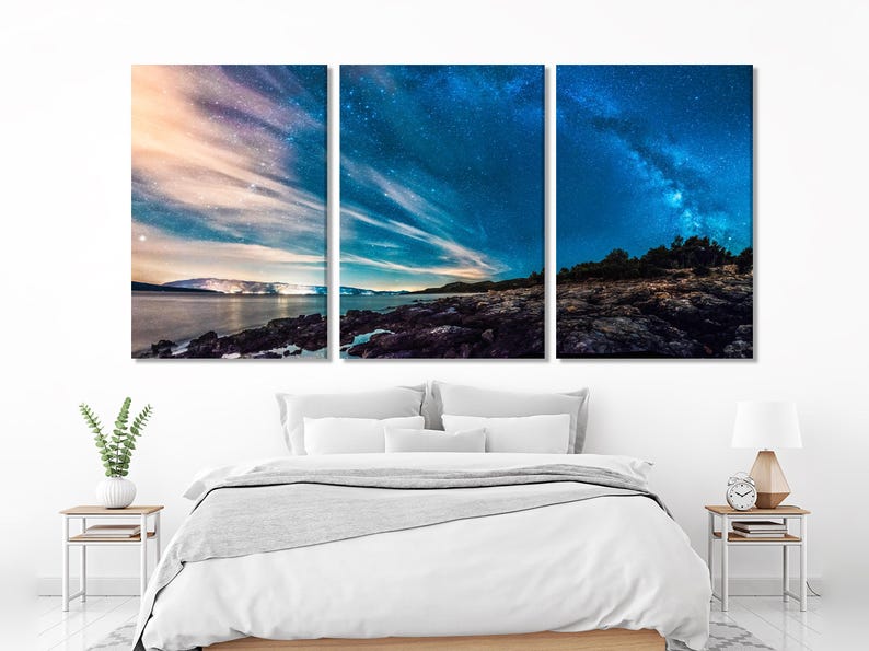 A starry Milky Way night sky over a dark rocky coastline and ocean horizon