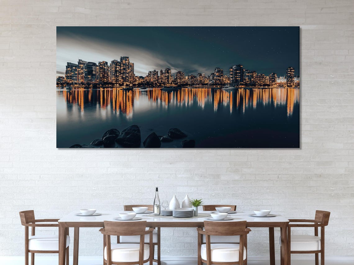 Night city skyline with warm building lights reflected on calm dark water detail view