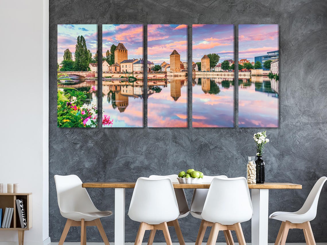 A three-panel sunset cityscape shows historic stone towers and buildings reflected in a calm river, with a pink-orange sky and green trees detail view