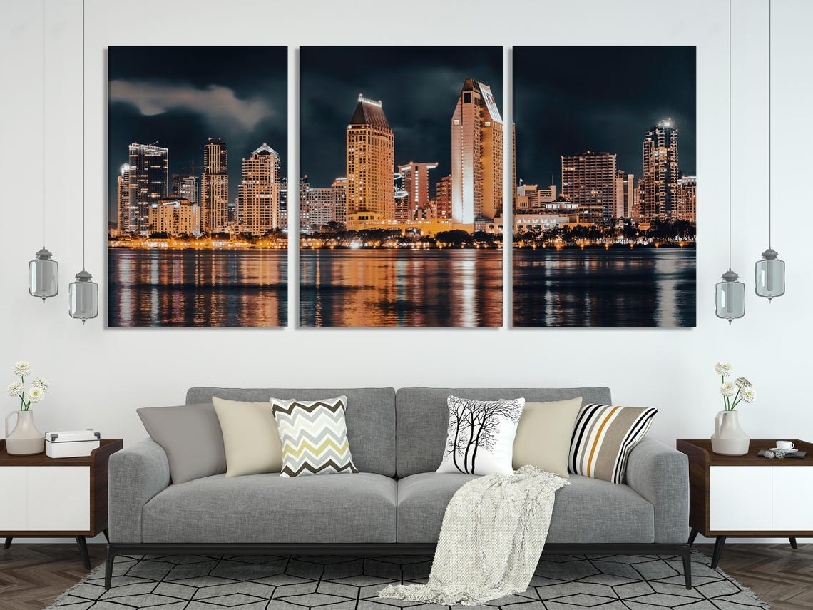 Mockup showing a modern living room with a multi-panel night city skyline artwork above the sofa