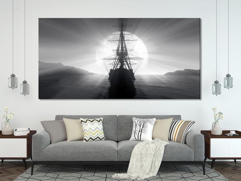Black and white moonlit seascape with a silhouetted sailing ship and radiating full moon glow